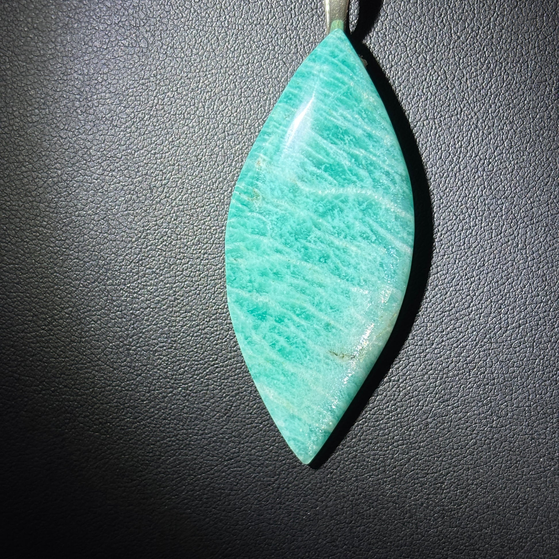 Teal stone pendant on a dark textured background