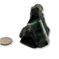 Polished emerald next to quarter for size comparison showing piece is larger than coin. 